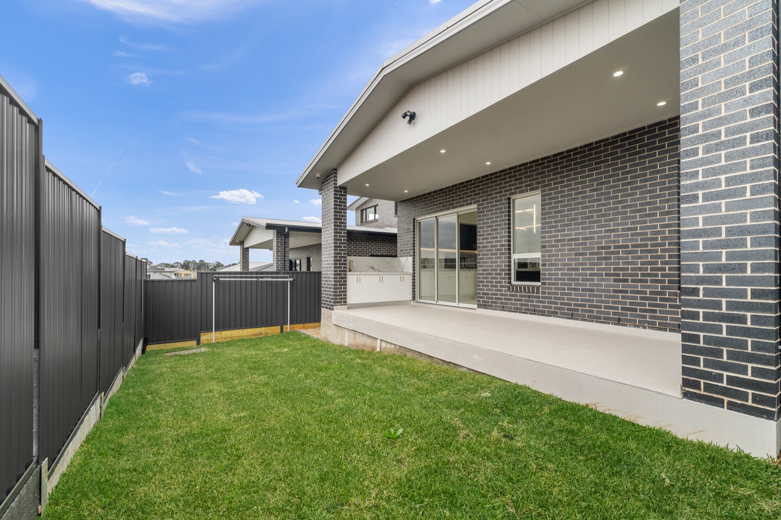 Landscaped backyard with lawn and an outdoor entertaining area