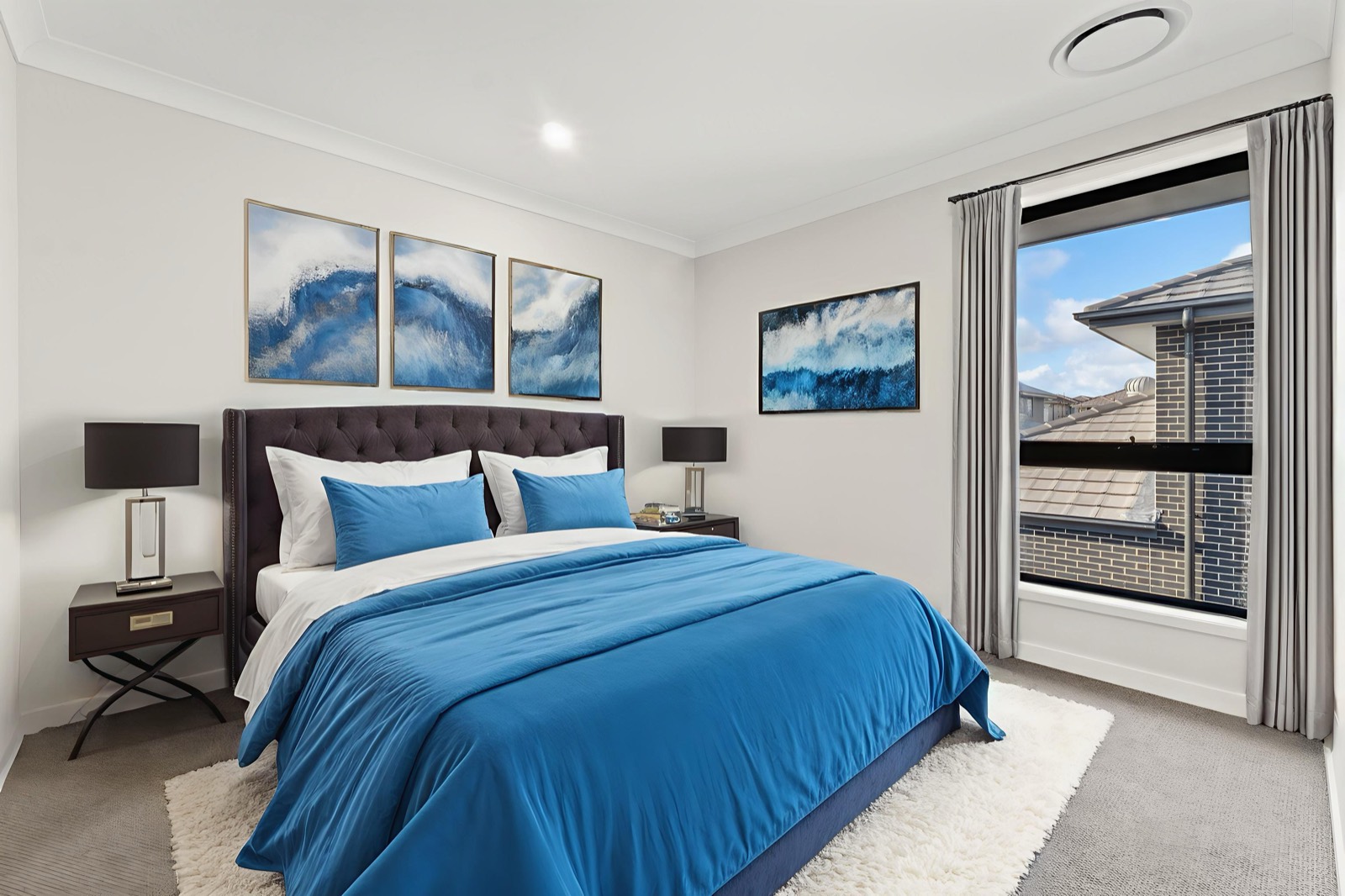 Bedroom with a blue bed and framed blue ocean artwork above the bedhead