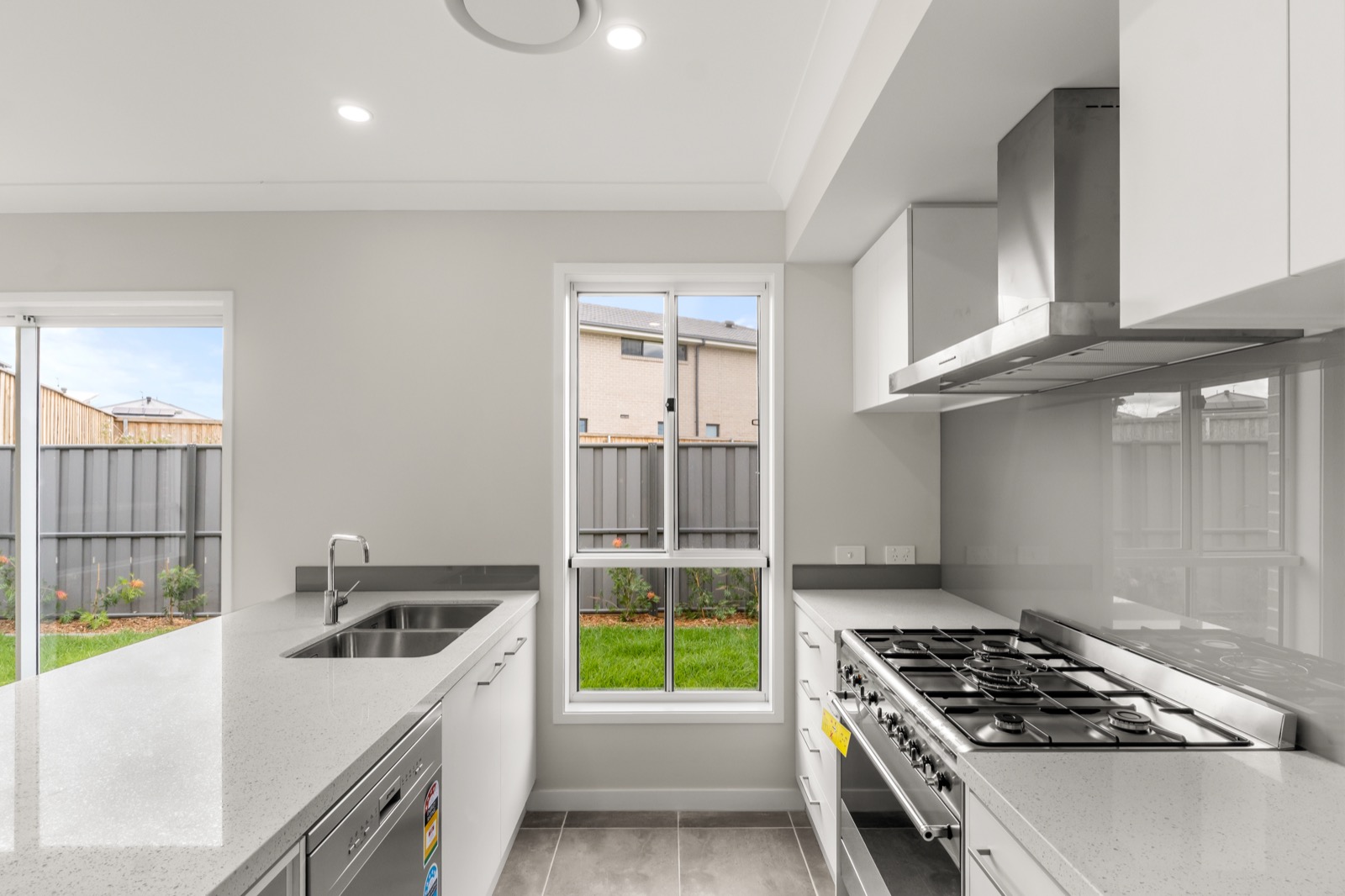 Bright modern kitchen with stone benchtops, stainless gas cooktop and garden view